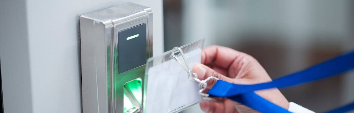 A person using a keycard access lanyard to attempt to gain entry to a building's door. The lanyard is blue.